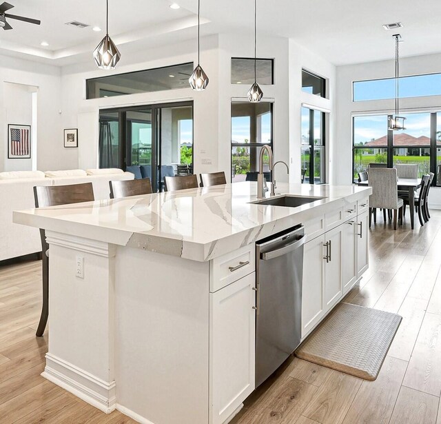 kitchen with a center island with sink, sink, white cabinets, and hanging light fixtures