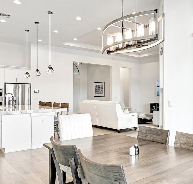 dining area featuring a raised ceiling and light wood-type flooring