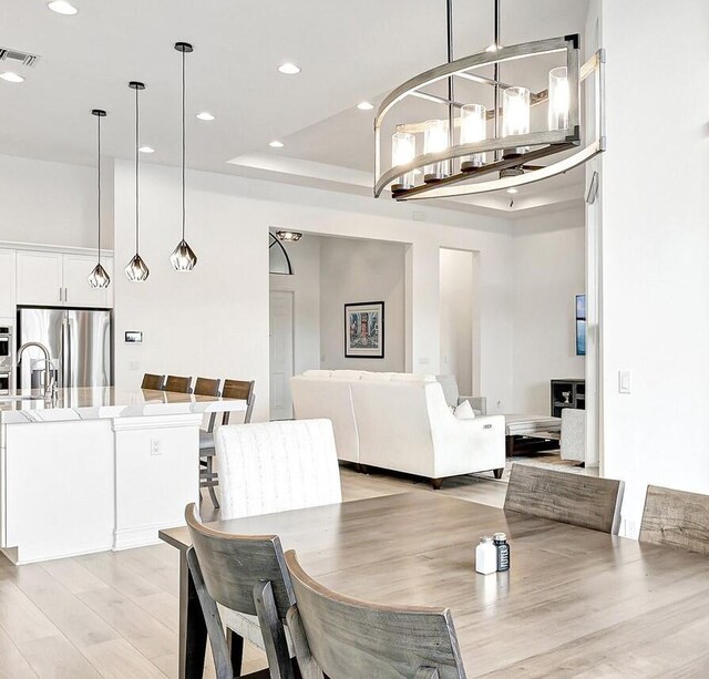 kitchen featuring an island with sink, sink, ceiling fan, light wood-type flooring, and white cabinets