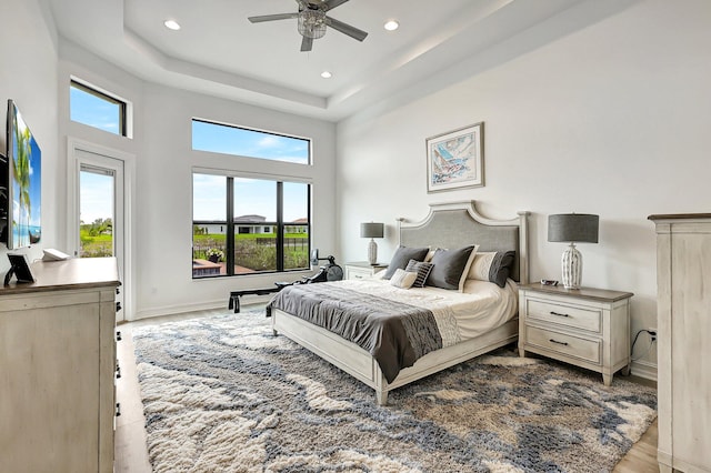 living room featuring light wood-type flooring, a raised ceiling, and ceiling fan