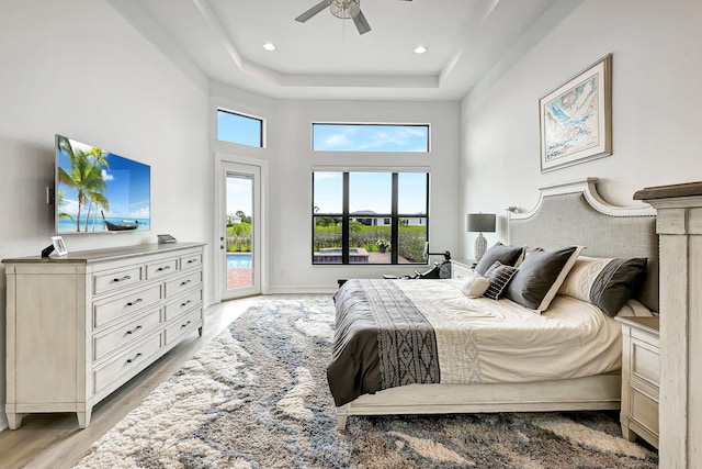 living room featuring light wood-type flooring, a raised ceiling, and ceiling fan