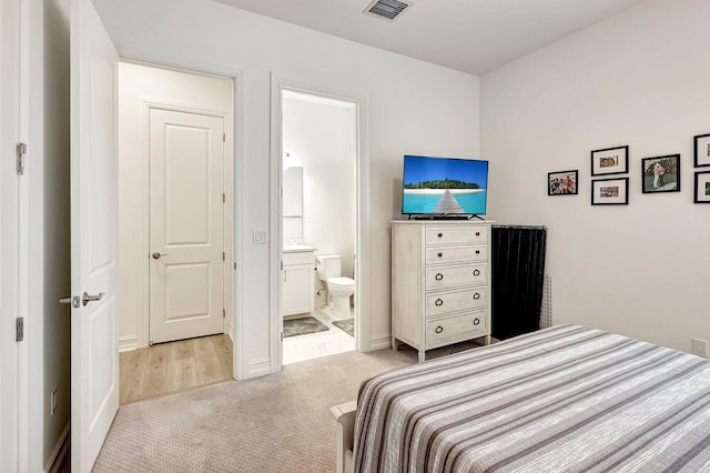 bedroom featuring light carpet and ensuite bathroom