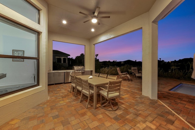 patio terrace at dusk with a grill, ceiling fan, and area for grilling