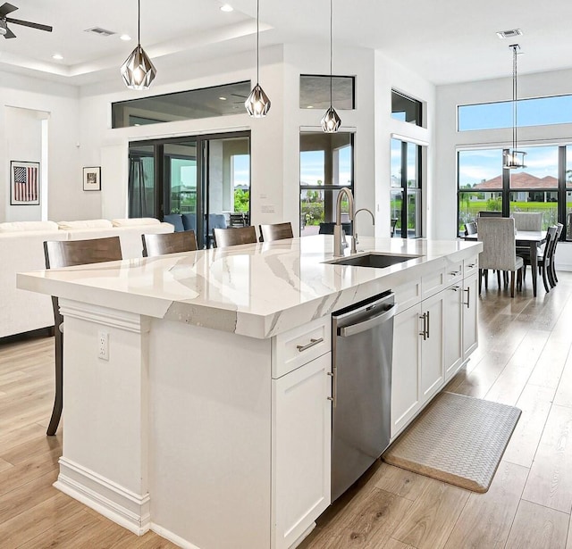 kitchen with an island with sink, hanging light fixtures, and light wood-type flooring