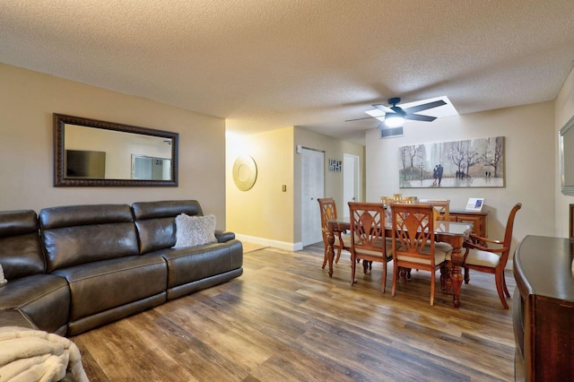 living room featuring wood-type flooring, a textured ceiling, and ceiling fan