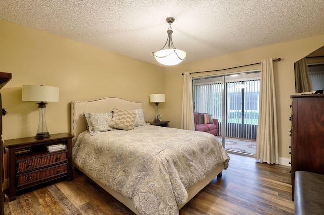 bedroom with a textured ceiling, dark hardwood / wood-style flooring, and access to outside