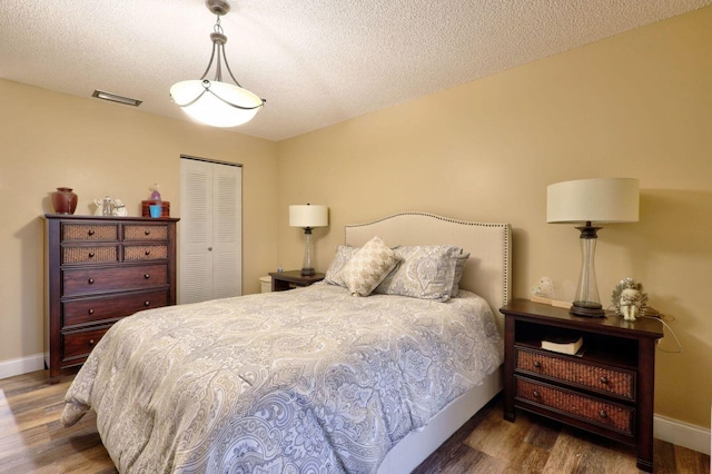 bedroom featuring a textured ceiling, a closet, and dark hardwood / wood-style floors