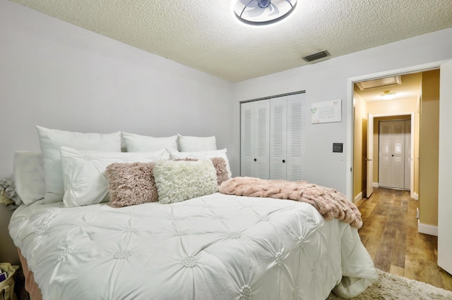 bedroom with a closet, a textured ceiling, and light hardwood / wood-style flooring