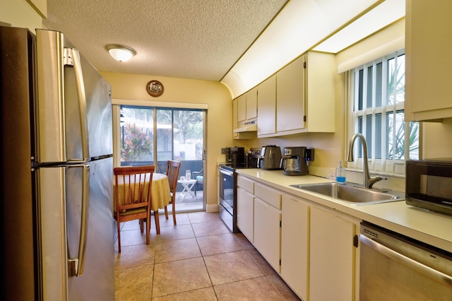 kitchen featuring sink, stainless steel appliances, a textured ceiling, light tile patterned floors, and custom exhaust hood