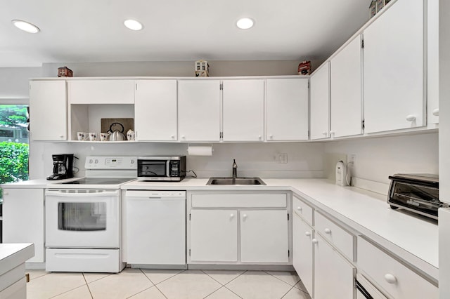 kitchen featuring white appliances, sink, light tile patterned flooring, and white cabinetry