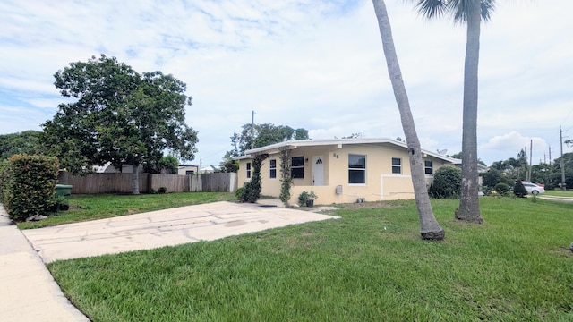 bungalow-style house with fence, a front lawn, and stucco siding