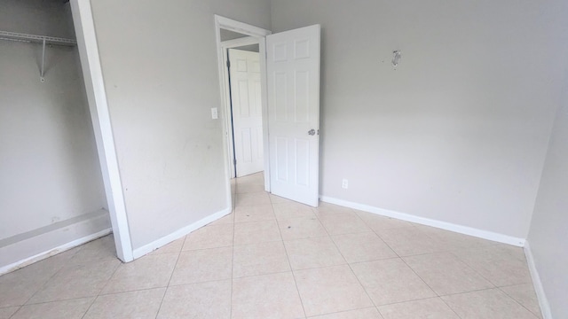 unfurnished bedroom with light tile patterned floors, a closet, and baseboards