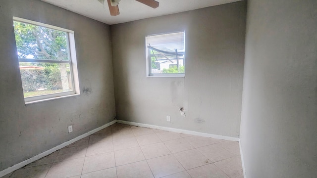 unfurnished room featuring ceiling fan, light tile patterned floors, and baseboards