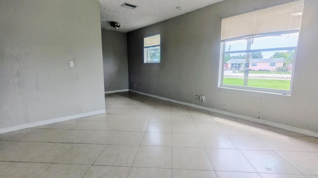 unfurnished room with light tile patterned floors, visible vents, and baseboards