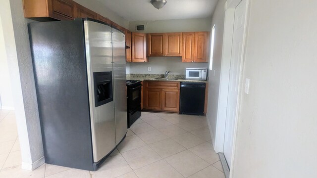 kitchen with light tile patterned floors, visible vents, brown cabinets, black appliances, and a sink