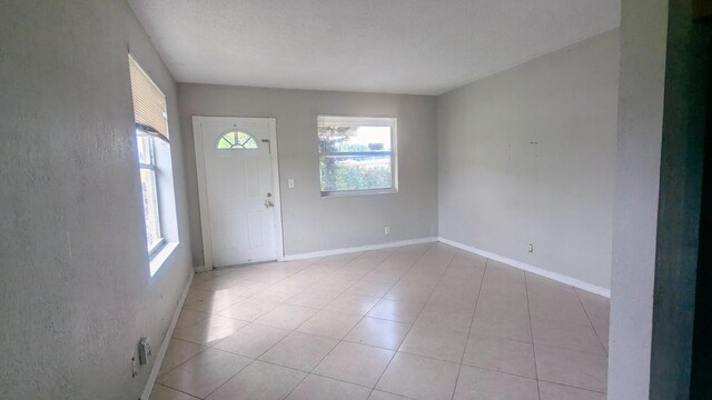 foyer featuring a textured ceiling, tile patterned floors, and plenty of natural light