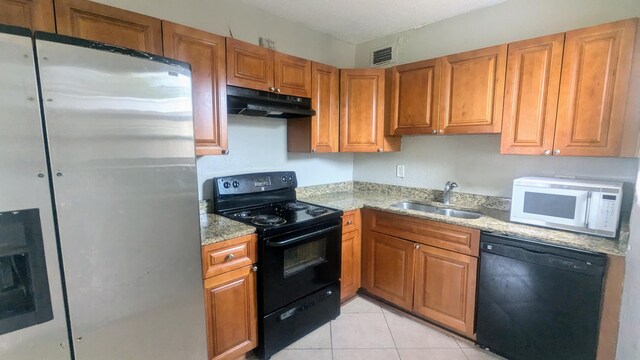 kitchen with sink, light stone counters, black appliances, and light tile patterned floors