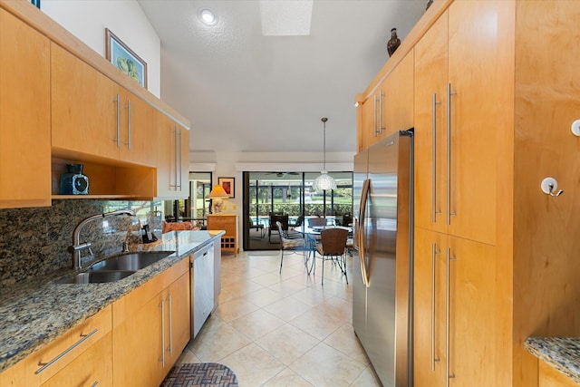 kitchen featuring stone counters, sink, hanging light fixtures, light tile patterned flooring, and appliances with stainless steel finishes