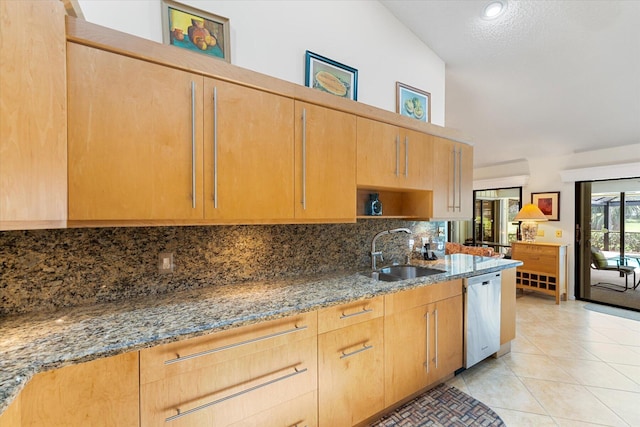 kitchen featuring stainless steel dishwasher, sink, stone countertops, lofted ceiling, and light tile patterned flooring