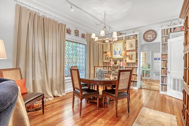 dining area featuring light hardwood / wood-style floors, crown molding, and a notable chandelier