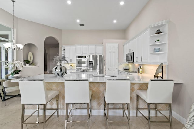 kitchen featuring pendant lighting, white cabinetry, a kitchen breakfast bar, stainless steel appliances, and kitchen peninsula