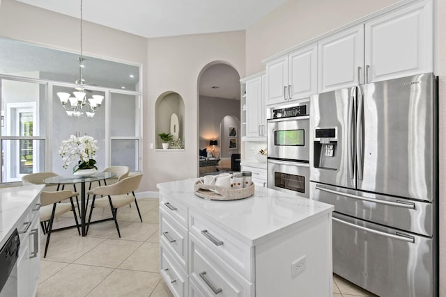 kitchen with appliances with stainless steel finishes, pendant lighting, white cabinetry, light tile patterned floors, and light stone counters