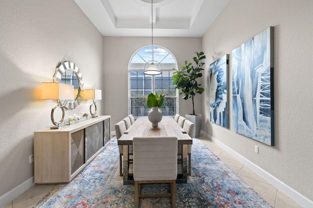 dining area with a raised ceiling and tile patterned flooring