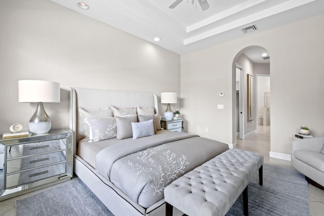 bedroom with ceiling fan, a raised ceiling, and light tile patterned floors