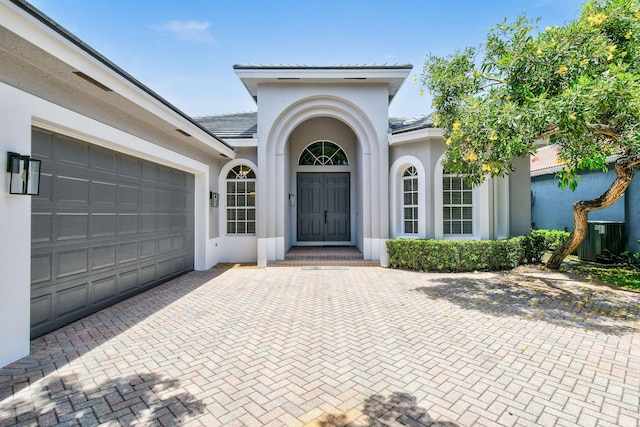 doorway to property with a garage and central AC unit