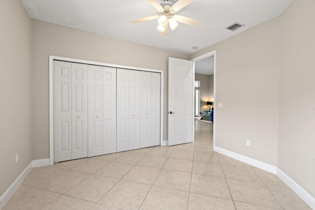 unfurnished bedroom with light tile patterned floors, a closet, and ceiling fan