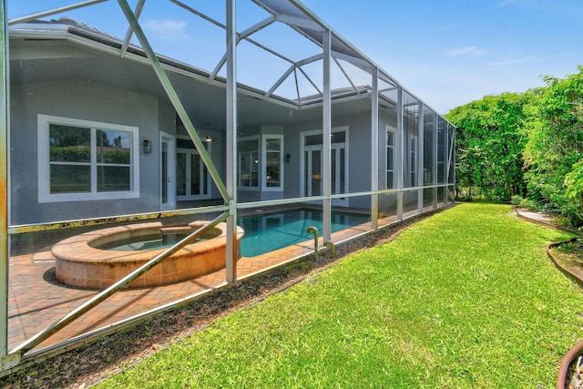 view of pool with an in ground hot tub, a yard, a patio area, and glass enclosure