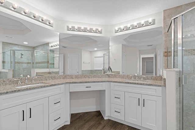 bathroom with hardwood / wood-style flooring, vanity, crown molding, a tray ceiling, and a shower with door