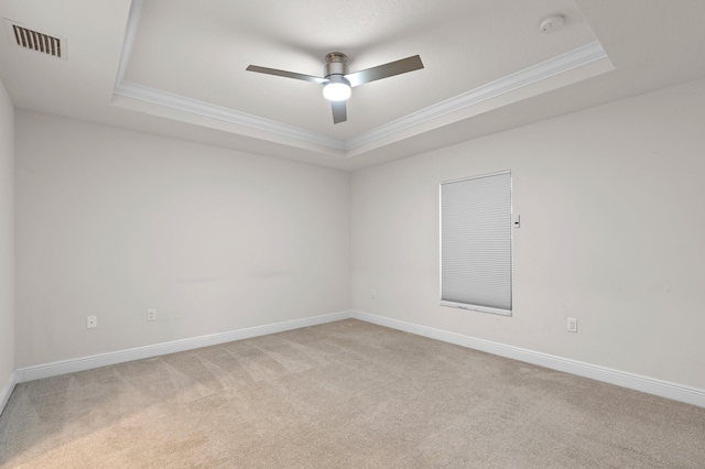 carpeted empty room with ceiling fan, ornamental molding, and a tray ceiling