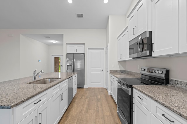 kitchen with sink, light hardwood / wood-style flooring, light stone countertops, white cabinetry, and stainless steel appliances