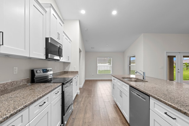 kitchen with sink, appliances with stainless steel finishes, hardwood / wood-style flooring, light stone countertops, and white cabinetry