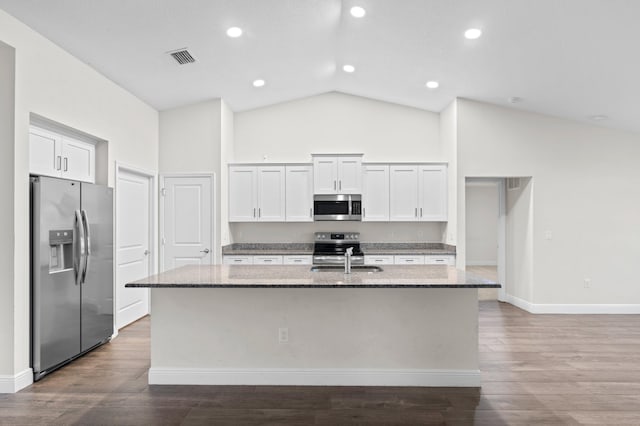 kitchen featuring appliances with stainless steel finishes, hardwood / wood-style floors, white cabinetry, a center island with sink, and light stone countertops