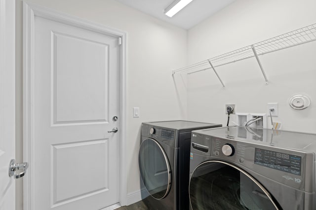 washroom with hardwood / wood-style flooring and washing machine and clothes dryer