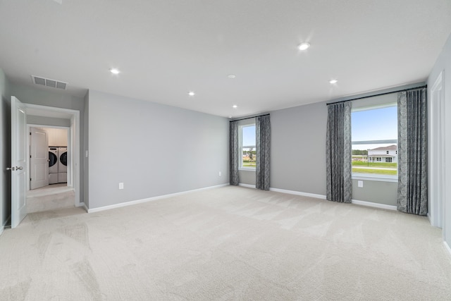 carpeted empty room featuring separate washer and dryer