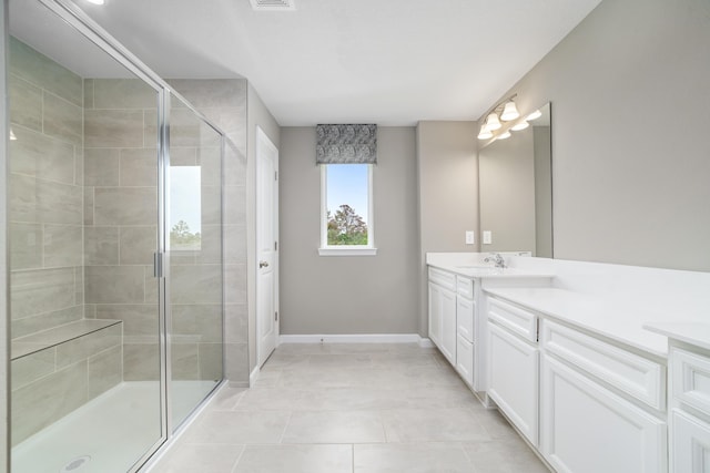 bathroom with a shower with door, vanity, and tile patterned flooring