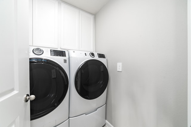 laundry area with washing machine and clothes dryer and cabinets