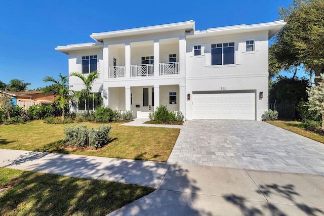 view of front facade with a garage, a balcony, and a front yard