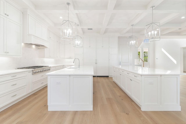 kitchen with stainless steel gas stovetop, a large island, light wood-type flooring, and decorative light fixtures