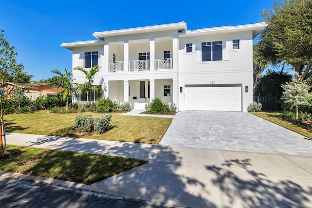 view of front of property with a balcony, a front yard, and a garage