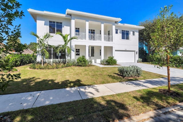 view of front of property featuring a garage, a balcony, and a front yard