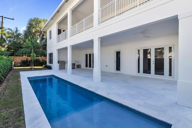 view of pool featuring french doors, a patio, an outdoor kitchen, and ceiling fan