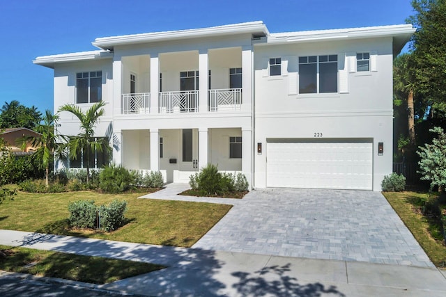 view of front of house featuring a front yard, a balcony, and a garage