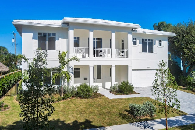 view of front of property with a garage, a balcony, and a front lawn