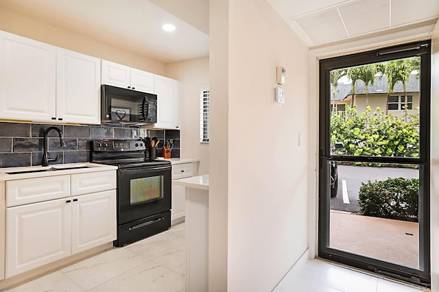 kitchen with black appliances, backsplash, white cabinetry, and sink