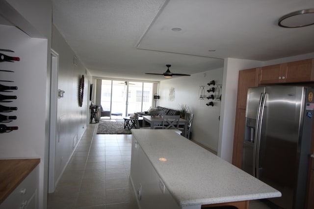 kitchen featuring a kitchen island, stainless steel fridge with ice dispenser, tile patterned flooring, and ceiling fan