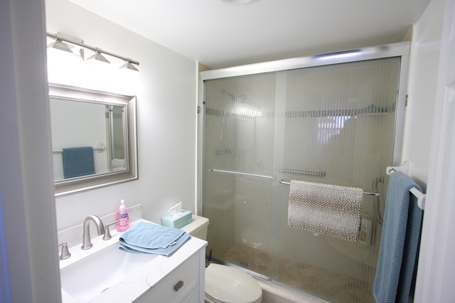 bathroom with a shower with shower door, toilet, and vanity